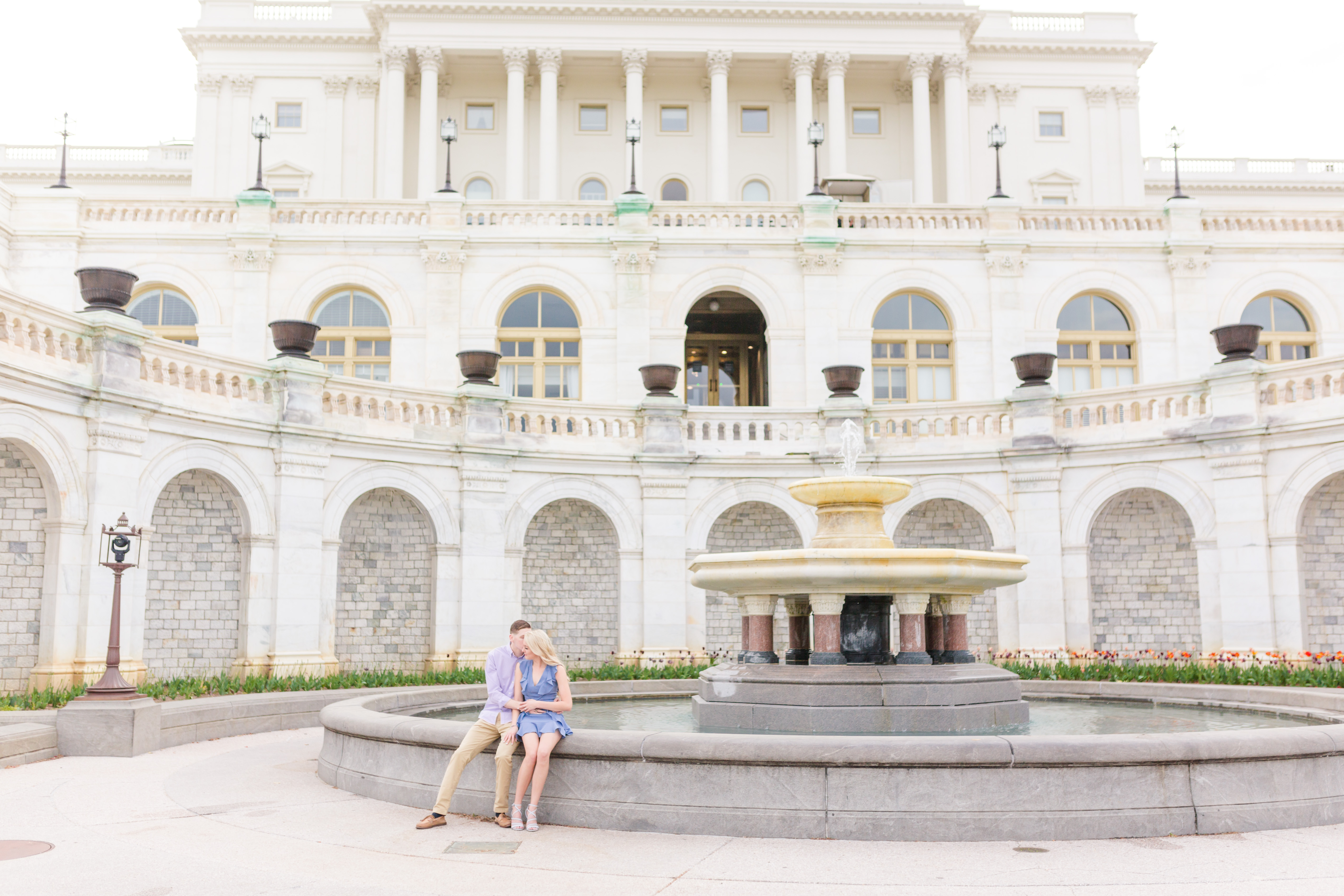 couple sitting on fountain in front of washington capitol