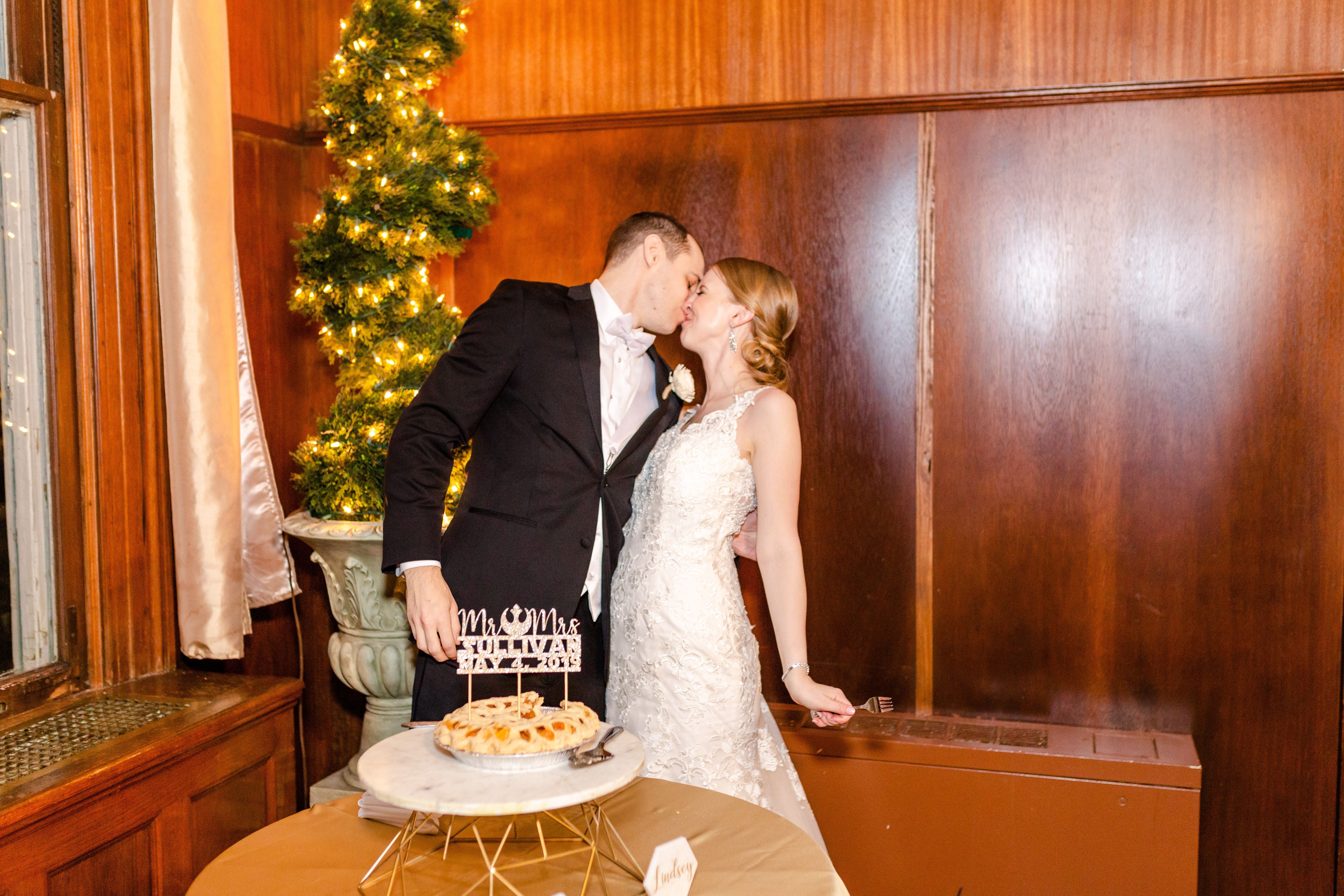 bride and groom kissing after pie cutting
