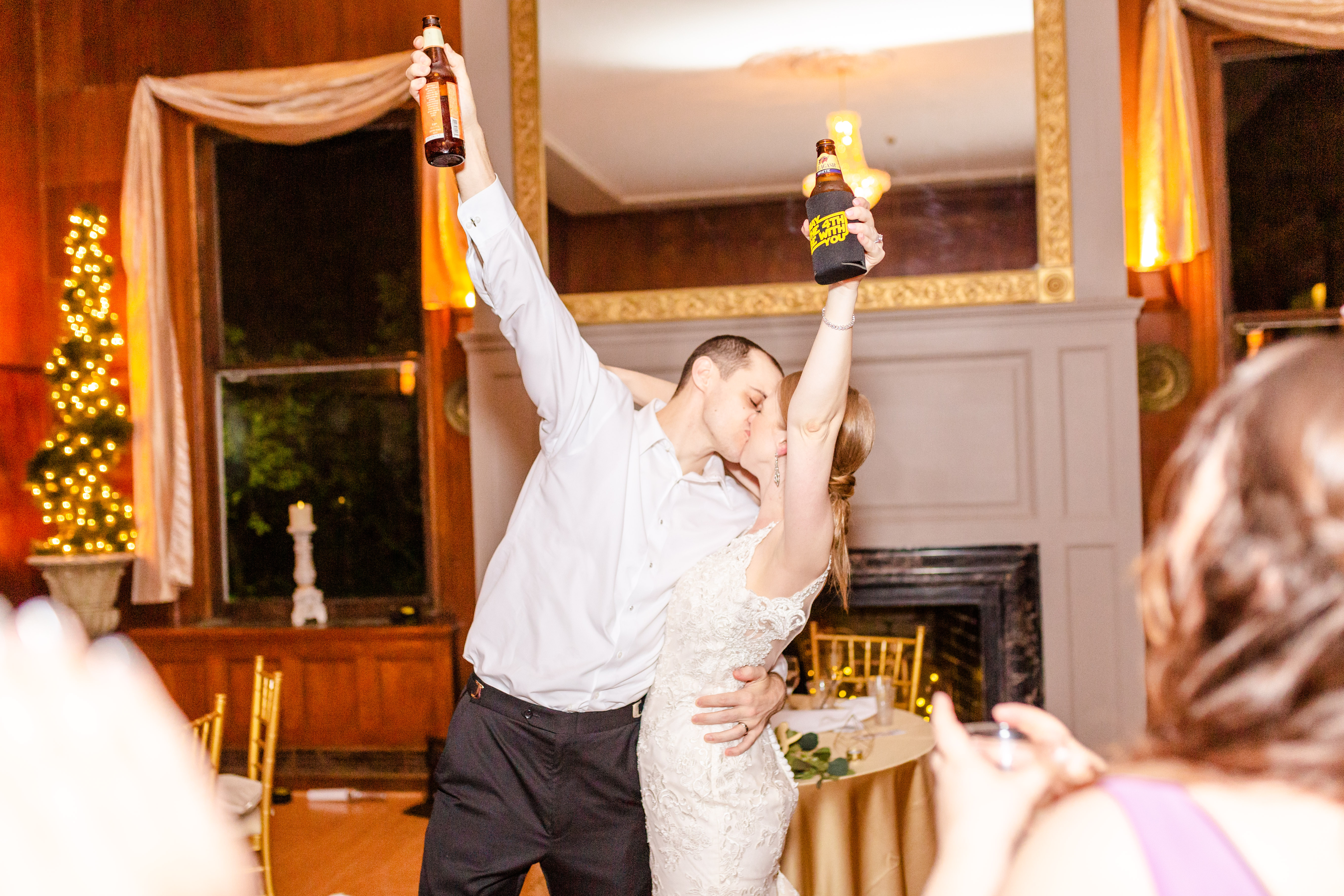 bride and groom kissing hand holding beers up in the air
