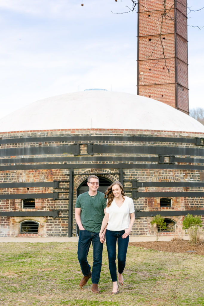 couple in casual clothes walking towards camera in front of large brick building