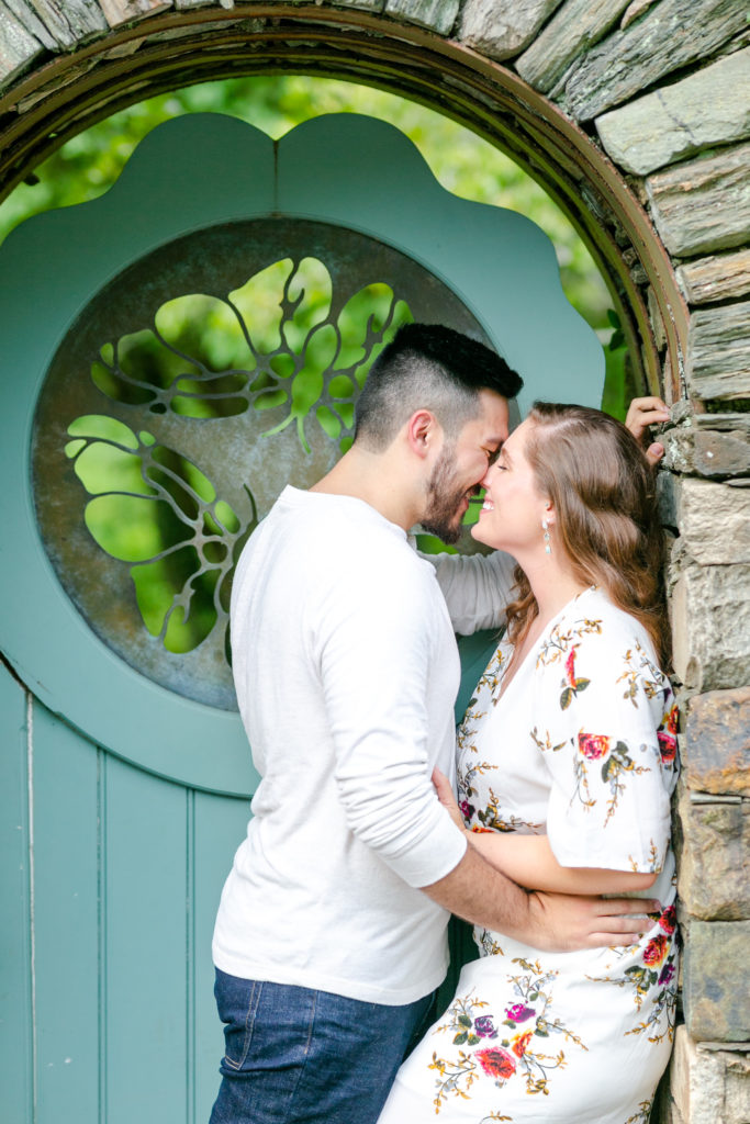 couple nearing a kiss in front of green ornate door to garden entrance