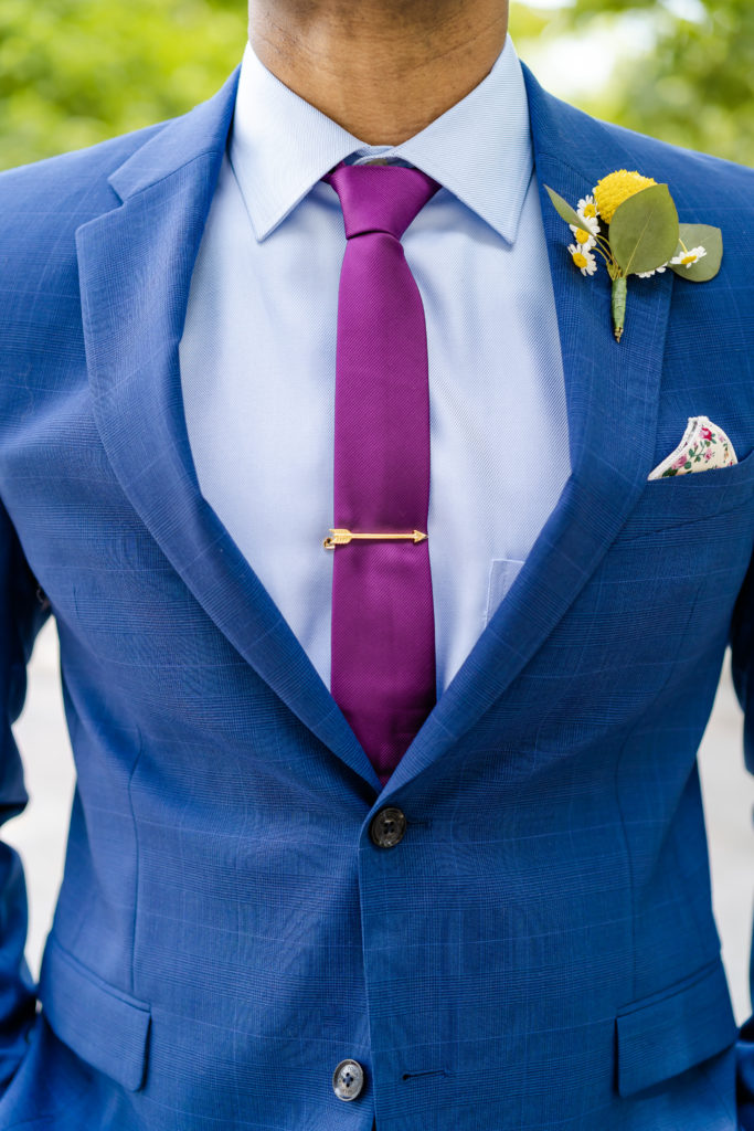 blue suit with purple tie and yellow boutonniere