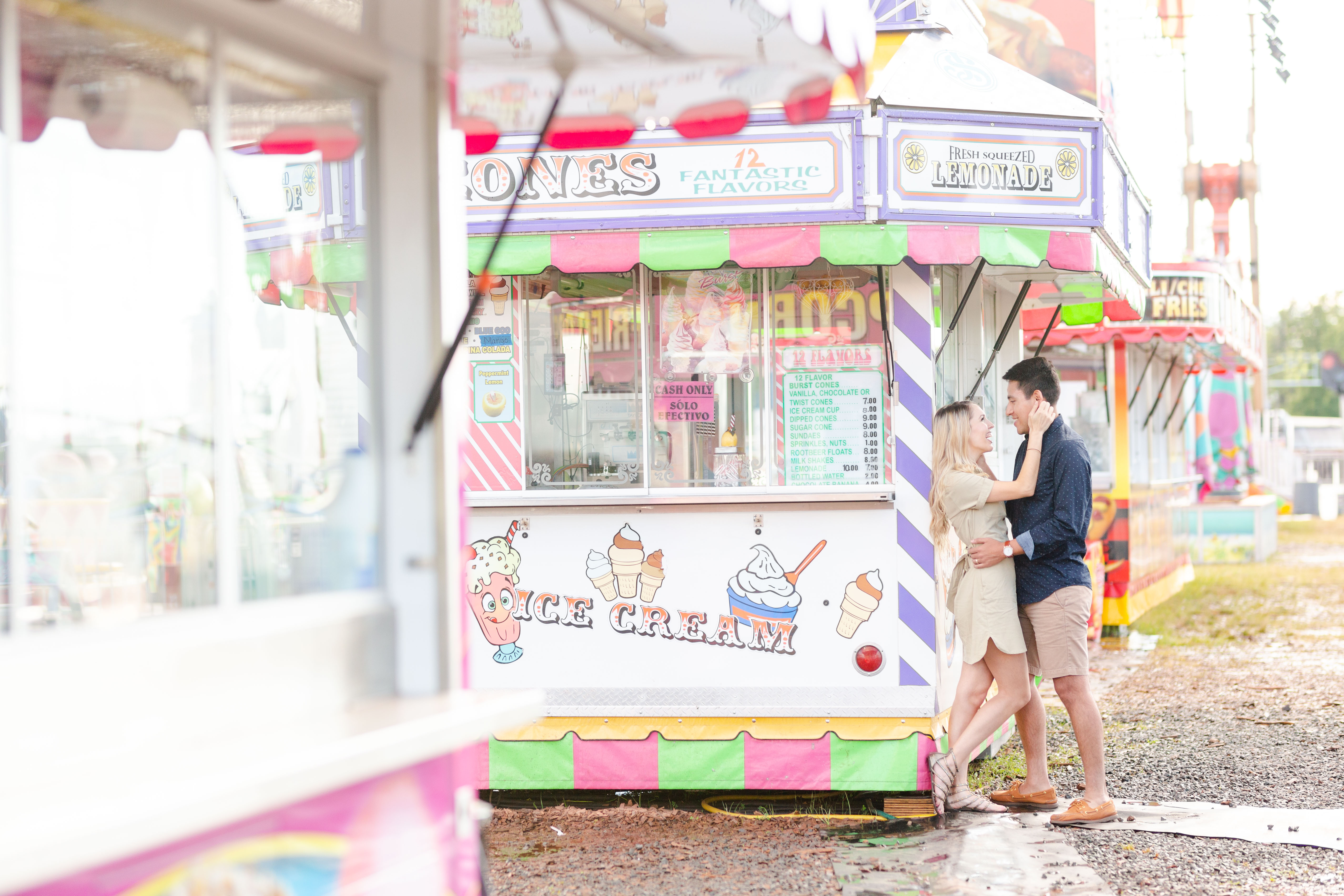 couple embracing next to ice cream stand at carnival