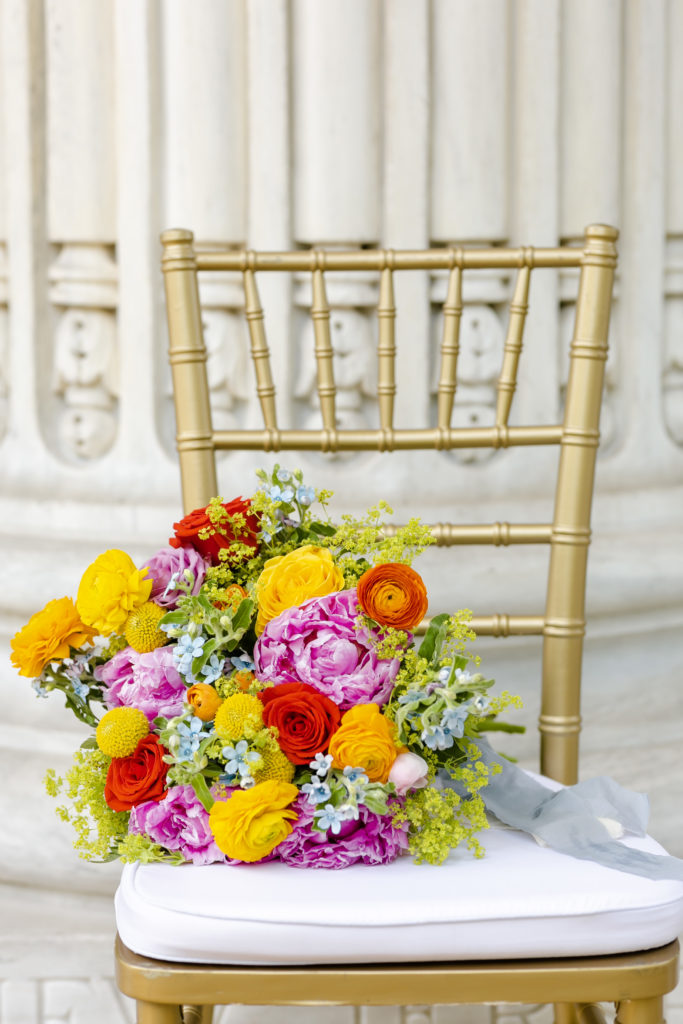 Yellow, Pink, and Green bouquet sitting on a chivari chair
